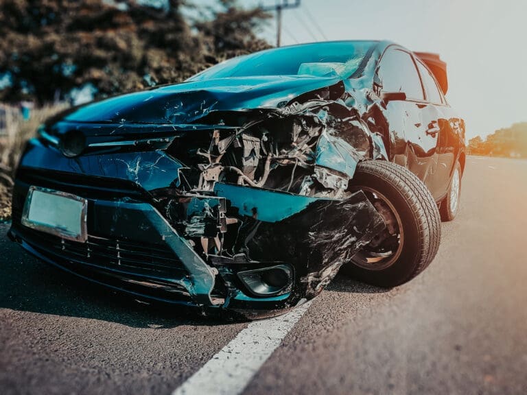 Front of Black Car Large Trucking Accident Damage