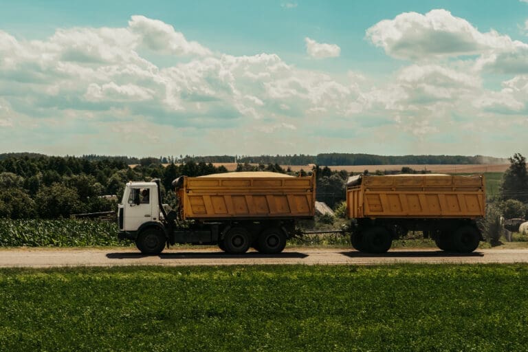 A truck with a trailer transports grain along the road