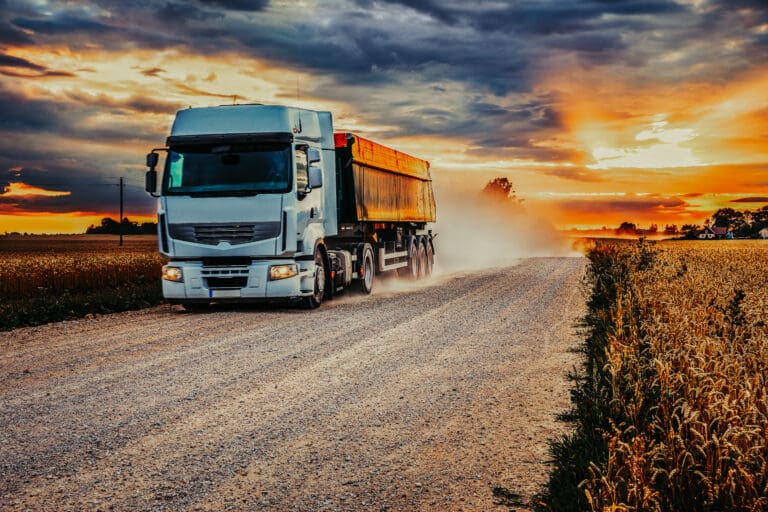 Grain truck on a rural road next to a rye field in the harvest