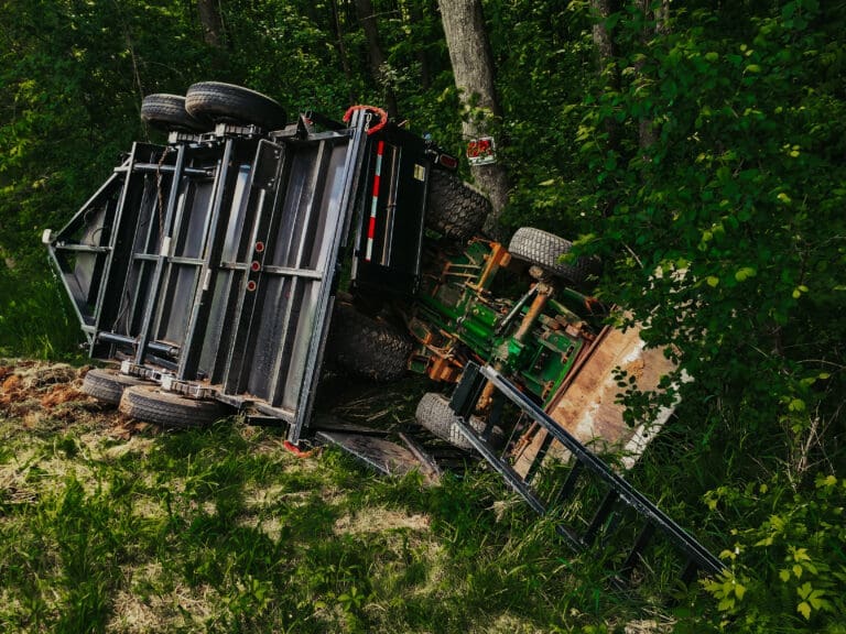 Overturned tractor and trailer laying in the ditch after an accident